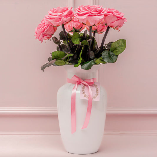 Elegant Women's Day flower arrangement featuring fresh pink roses in a white ceramic vase with a pink ribbon. A delicate and sophisticated floral gift for Women's Day delivery in Medellín