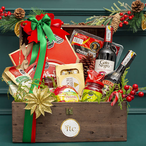 Luxury Christmas chest with wine, truffles, and gourmet treats for delivery in Medellín and Bogotá, Colombia, decorated with festive pine and golden flowers.