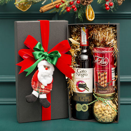 Luxury Christmas gift box with Gato Negro wine, wafer rolls, and a jar of nuts, decorated with a festive bow and Santa Claus detail, for delivery in Medellín